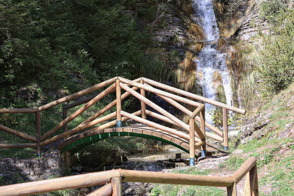 Puente de madera con una cascada de fondo