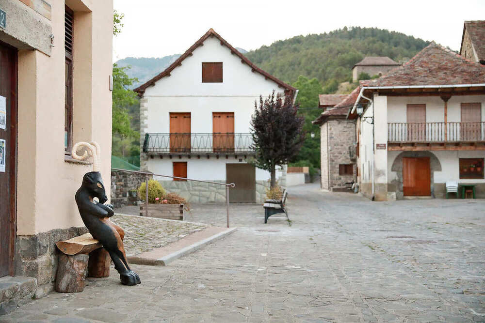 Plaza con estatua antropomorfa y cabeza de caballo sobre un banco