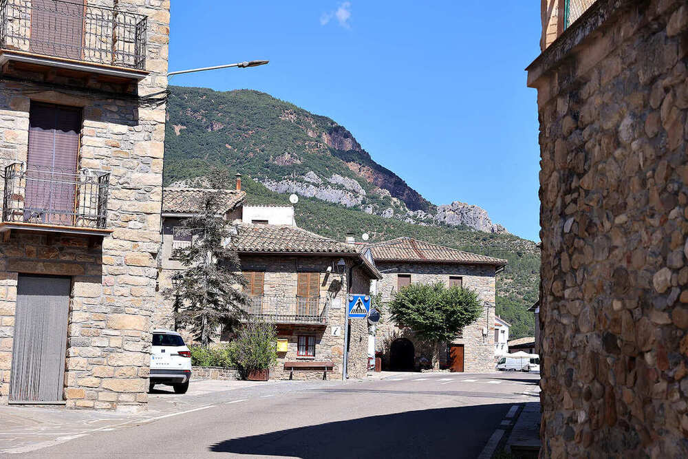 Calle del pueblo, con casas de piedra y el monte a lo lejos